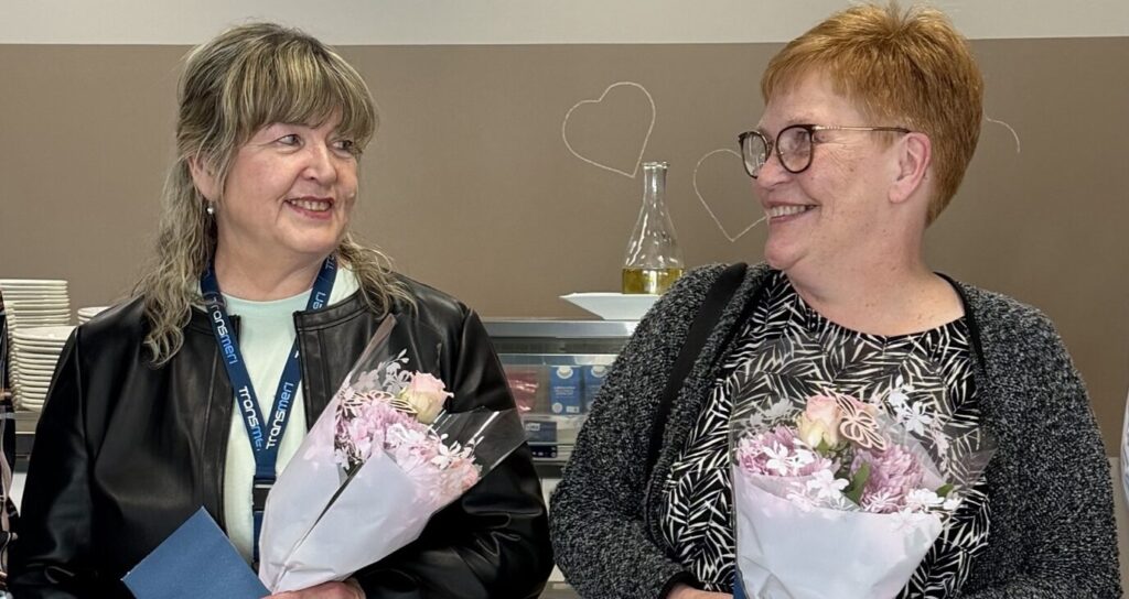 Anneli ja Annika katsovat iloisesti toisiaan kukkakimpput käsissään.
